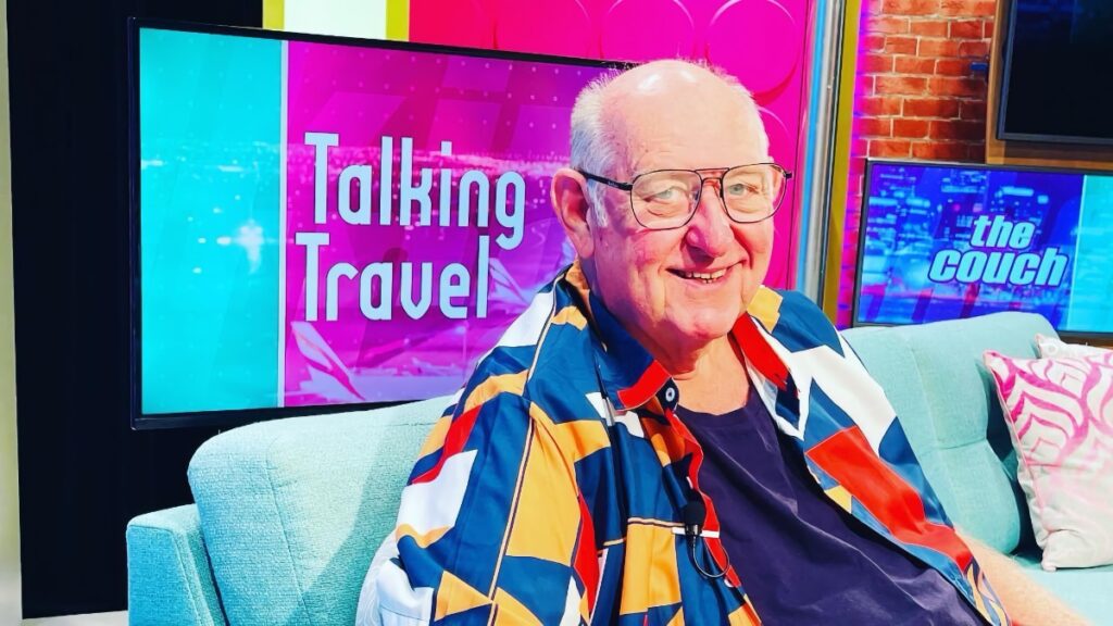 Smiling man on colorful "Talking Travel" TV set
