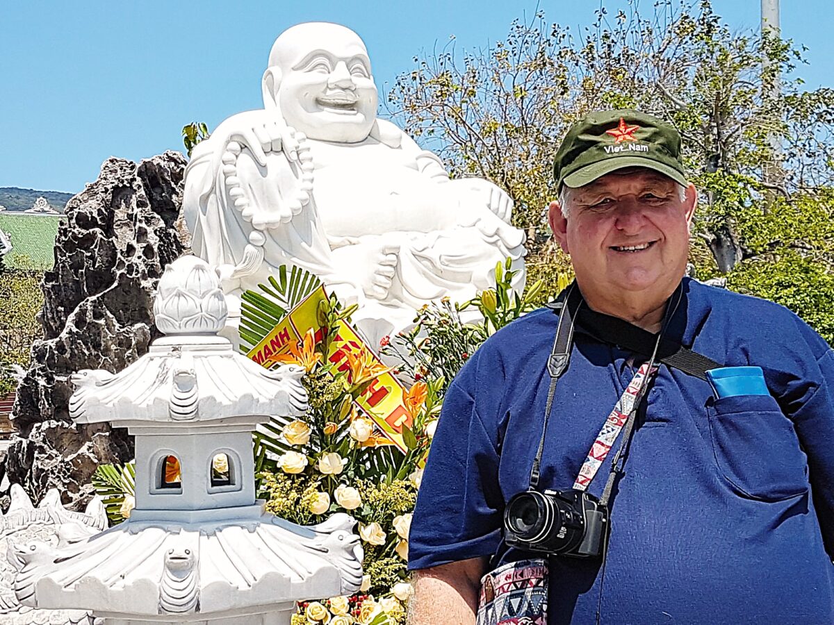 Tourist with camera beside white Buddha statue