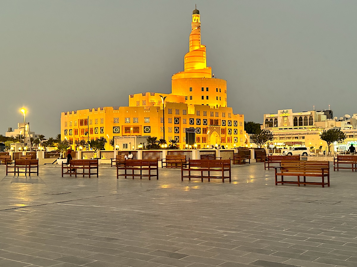 Illuminated spiral mosque and empty plaza benches