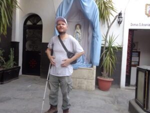 Person with cane standing by shrine statue