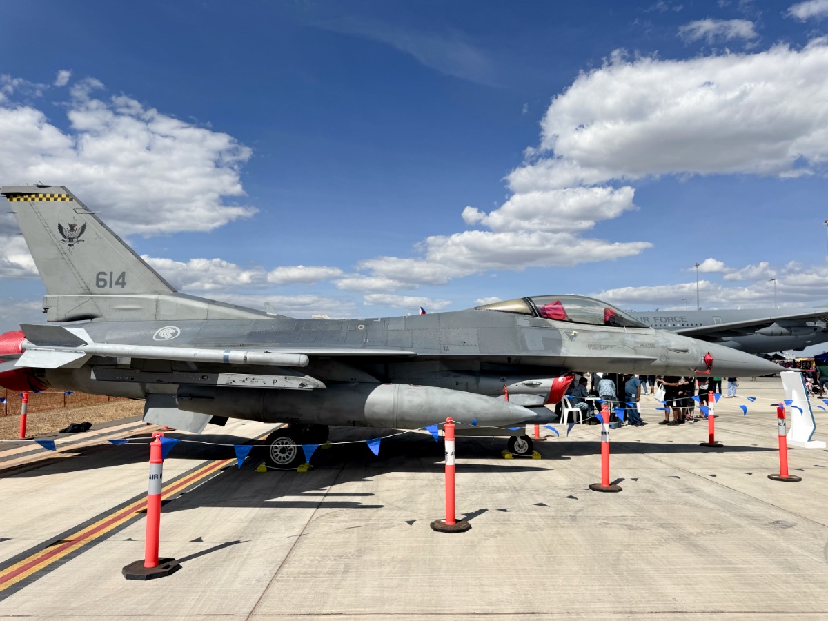 Gray fighter jet parked on tarmac with cones